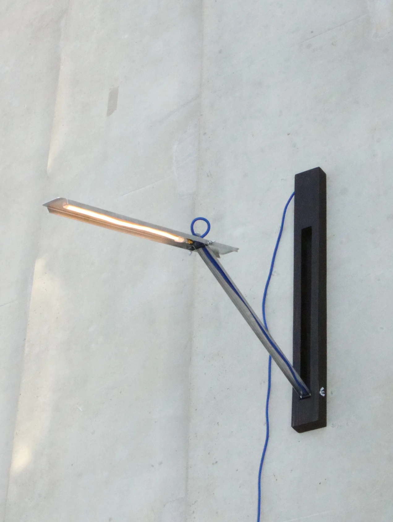 Zenvo aluminum and wood desk lamp mounted on a concrete wall